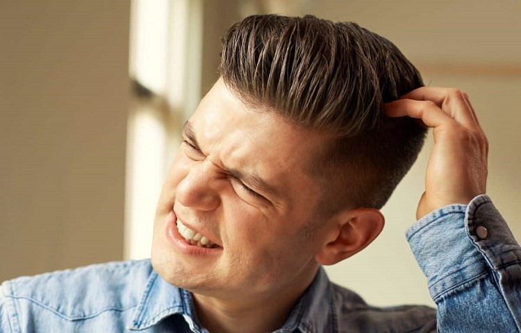 Hình ảnh một nam thanh niên đang gãi đầu với vẻ mặt rất khó chịu